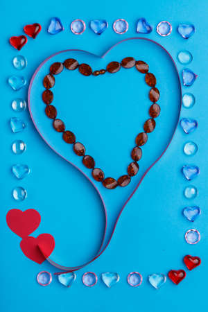 In a frame made of pebbles of hearts on a blue background, a ribbon in the shape of a heart.の写真素材