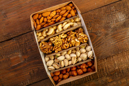 Assorted nuts in packaging on a brown wooden table. Copy spaceの写真素材