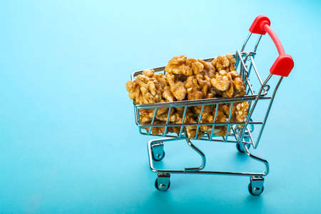 Food cart filled with peeled walnuts on a blue background. Copy space.の写真素材