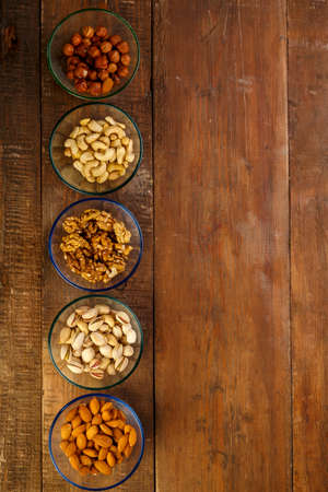 Assorted nuts in a glass bowl on a wooden table. copy space.の写真素材