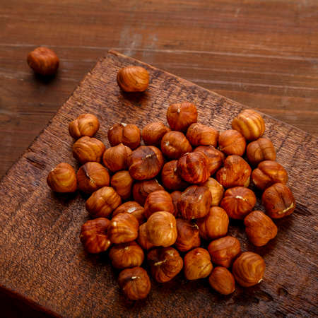 A handful of nuts are scattered on a board on a wooden table.の写真素材