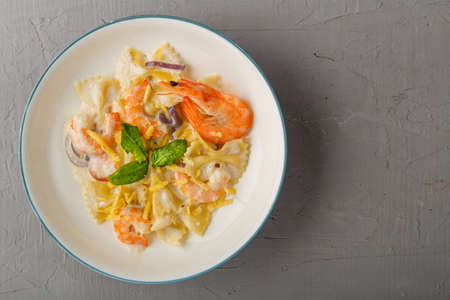 Pasta with shrimps in a creamy sauce on a gray plate on a concrete background. Copy space.の写真素材