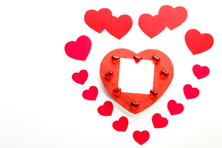 heart made of paper hearts laid out on a white background in the middle of a cardboard heart and glass hearts and a note copy space.の写真素材