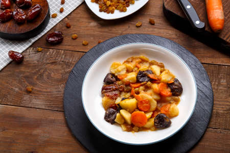 A dish of Jewish cuisine sweet tsimes with vegetarian dates carrots in a plate on a round stand next to candied fruits.の写真素材