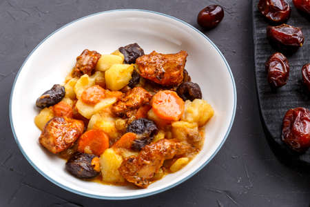 A dish of Jewish cuisine sweet tsimes with vegetarian dates carrots in a plate on stand next to candied fruitsの写真素材
