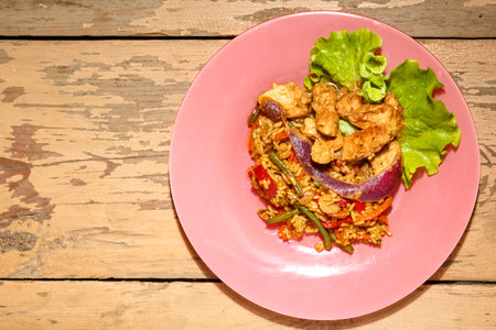 Vegetables with chicken meat in a pan-Asian sauce with sesame seeds on salad leaves on a wooden table in a plate.の写真素材