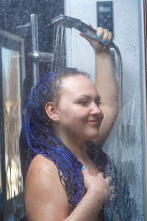 woman with blue afro hairstyle in the shower under the tap.の写真素材