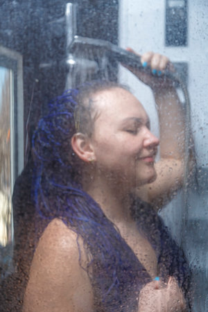 woman with blue afro hairstyle in the shower under the tap.の写真素材