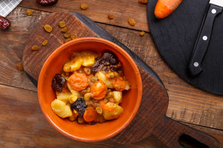Jewish cuisine dish sweet tsimes with carrot dates in a clay plate on a wooden board.の写真素材