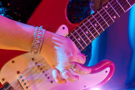 An electric guitar in female hands who play it during a concert.の写真素材