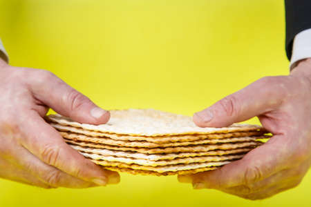 Matzah in the hands of a man on a yellow background.の写真素材