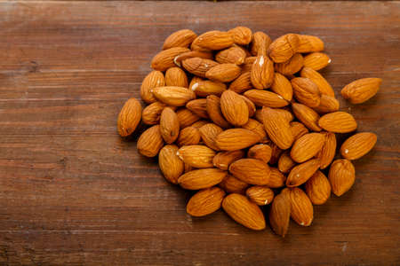 Almond nuts are sprinkled on a dark wooden table.の写真素材