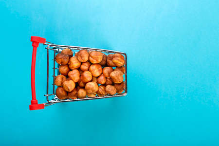 Food cart filled with peeled hazelnuts on a blue background. Copy spaceの写真素材