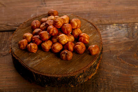 Hazelnuts scattered on a wooden round board on the table.の写真素材