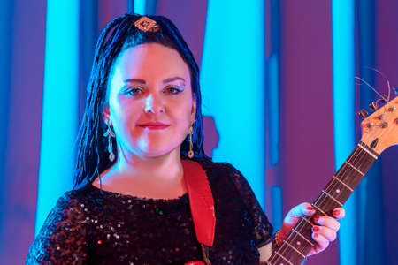 Woman with blue afro hairstyle guitarist playing electric guitar at a concert.の写真素材