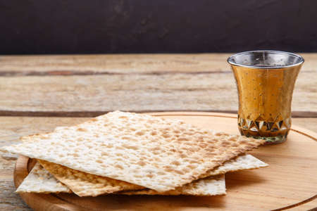 On a round wooden board matzah and a glass of kiddush wine.の写真素材