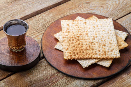 On a wooden table matzah and a glass of wine for kiddush on a round board.の写真素材