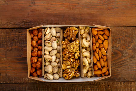Assorted nuts in packaging on a brown wooden table.の写真素材