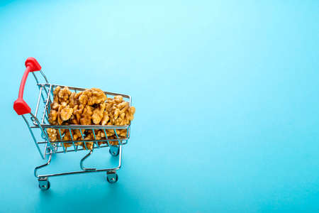 Food cart filled with peeled walnuts on a blue background. Copy space.の写真素材