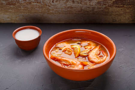 Tom yam soup with shrimps in a plate on a concrete background.の写真素材