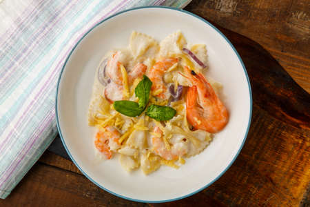 Pasta with shrimps in a creamy sauce on a gray plate on a wooden table on a napkin.の写真素材