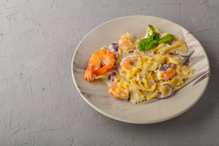 Pasta with shrimps in a creamy sauce on a gray plate on a concrete background.の写真素材