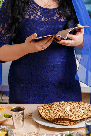 A faceless Jewish woman at the Passover Seder table reads the Passover Haggadah.の写真素材