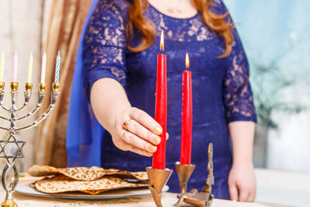A faceless Jewish woman at a table on Passover Eve lights candles.の写真素材