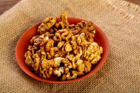 Walnuts in a clay plate on burlap on a wooden table.の写真素材