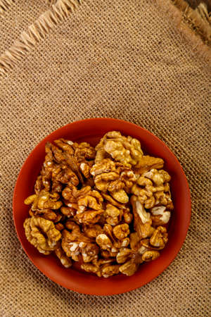 Peeled nuts in a clay plate on burlap on a wooden table.の写真素材