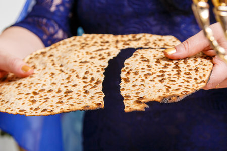 A Jewish woman at the Passover Seder table breaks the shmura matzah.の写真素材