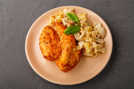 Baked chicken breast on a plate with pineapple salad on a table on a concrete background.の写真素材
