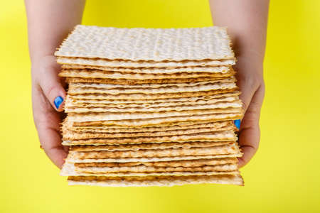 A stack of matzo in the hands of a woman on a yellow background.の写真素材