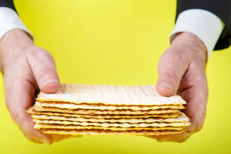 Pesach matzah in the hands of a man on a yellow background.の写真素材