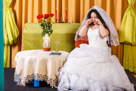 Jewish bride in a wedding dress with a veil crying her groom left her before the chupa ceremony.の写真素材