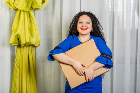 Curly brunette woman holding a long-awaited purchase in her hands showing emotion of joy.の写真素材