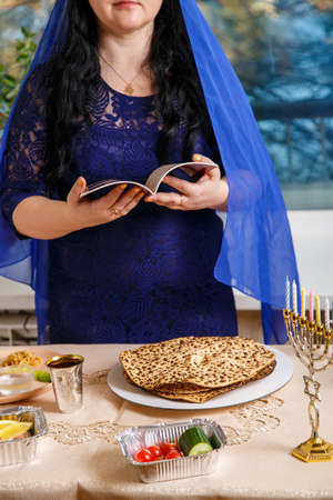 A faceless Jewish woman at the Passover Seder table reads the Passover Haggadah.の写真素材