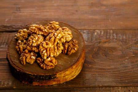 Walnuts are scattered on a round board on a wooden table.の写真素材