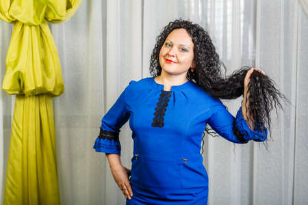 Curly brunette woman holds hair in her hands showing its length.の写真素材