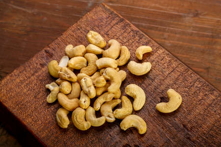 Cashew nuts scattered on a square board on a wooden table.の写真素材