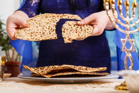 A Jewish woman at the Passover Seder table breaks the shmura matzah.