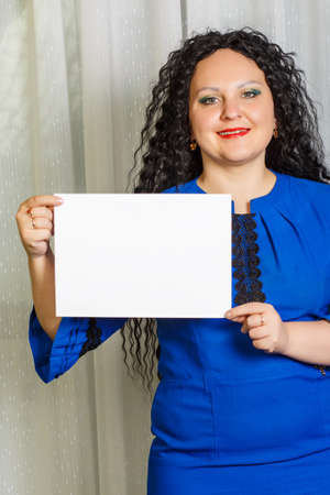Curly joyful brunette woman holding a copy space plate in her hands.の写真素材