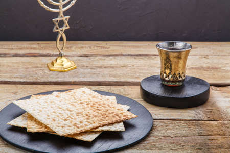 There is a candlestick on a round wooden board and a glass of kiddush wine next to the table. Horizontal photoの写真素材