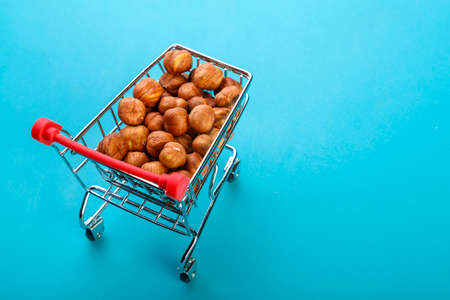 Food cart filled with peeled hazelnuts on a blue background. Copy space.
