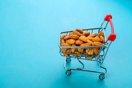 Food cart filled with peeled almonds on a blue background. Horizontal photoの写真素材