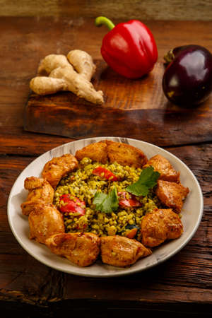 Food for suhoor in Ramadan bulgur post with beef in a plate on a wooden table next to vegetables on a board. Vertical photoの写真素材