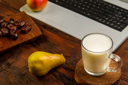Breakfast while working at the computer, milk and fruit. Horizontal photo