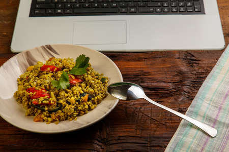 Dinner while working at the laptop on the table bulgur with vegetables.