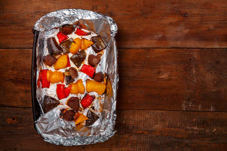 Antipasta in sauce baked on a foil in the form on a wooden table.の写真素材