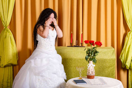 A Jewish bride in a wedding dress with her hair down in the hall is crying her groom left her before the chuppah ceremony. Horizontal photoの写真素材